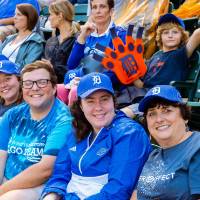 Five fans in gvsu night tigers hats are turned and facing the camera, all smiling